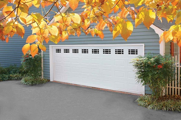 Red and yellow leaves hanging from tree near two-car white garage door