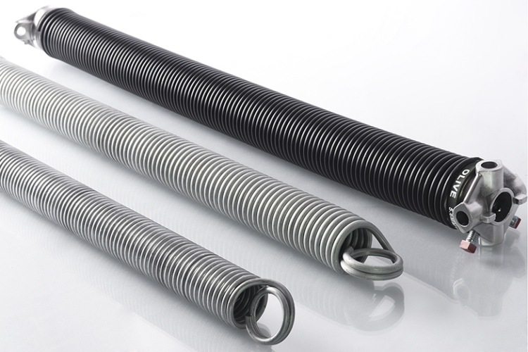 Three garage door springs in assorted sizes on white surface