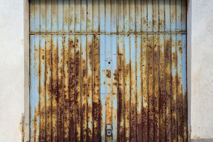 Rusty blue garage door on white one-car garage