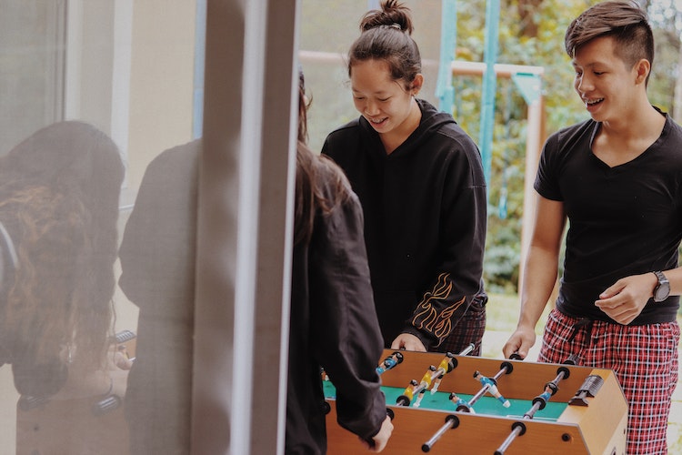 Family wearing pajamas playing foosball in garage game room