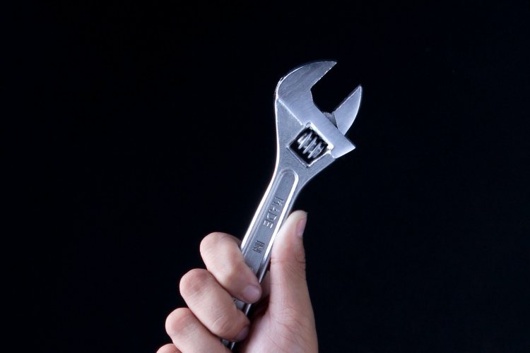 Stainless steel adjustable wrench clenched in raised hand