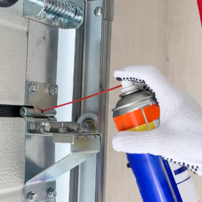Technician lubricating garage door hinges